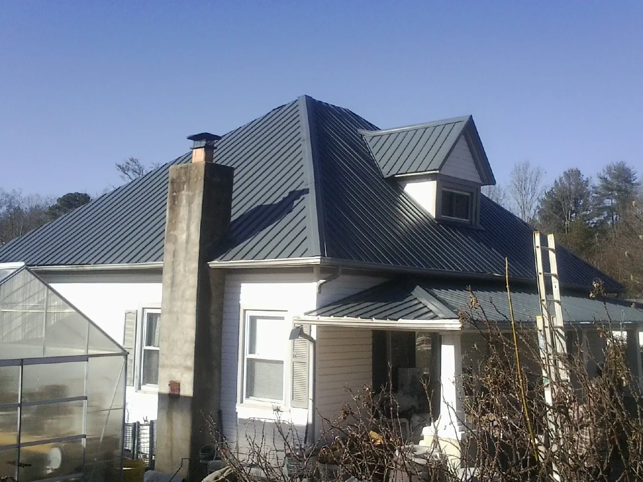 Dark blue standing seam metal roof on a white farmhouse with dormer — Slate & Tile Roof Repair by Roofing Brothers in Usk