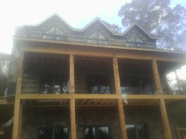 Dormers and porch framing on a large log home under construction — Roof Coating work by our crew in Usk