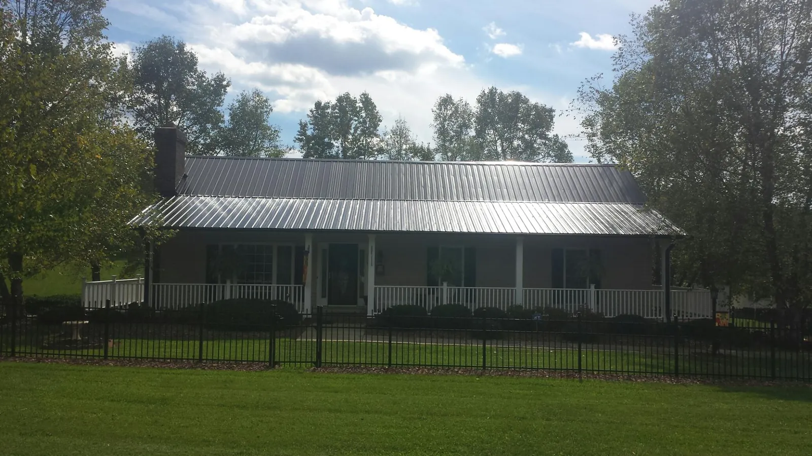 Gray metal roof on a brick ranch with a full width front porch — Gutter Guard Installation work by our crew in Usk
