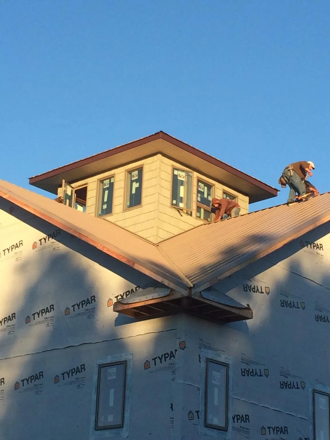 Roofers working around a rooftop cupola on a new metal roof at sunset — Roof Waterproofing in Usk by Roofing Brothers
